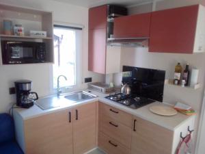 a small kitchen with a sink and a stove at Mobil home Neuf 6 places Climatisé in Camiers