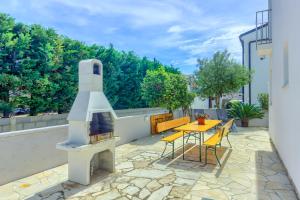 patio z kominkiem, stołem i krzesłami w obiekcie Apartment House Virić w mieście Vir