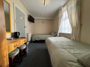 a room with two beds and a desk and a window at Delamere Hotel in Blackpool