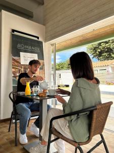 Ein Mann und eine Frau sitzen an einem Tisch in einem Restaurant. in der Unterkunft Campiotel Les Dunes - ROMANEE in Ars-en-Ré