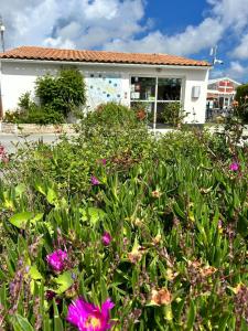 einen Garten mit lila Blumen vor einem Haus in der Unterkunft Campiotel Les Dunes - ROMANEE in Ars-en-Ré