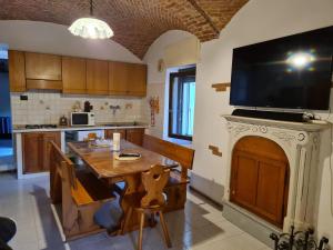 a kitchen with a wooden table and a television on a wall at Le Palme Apartment in Gargallo