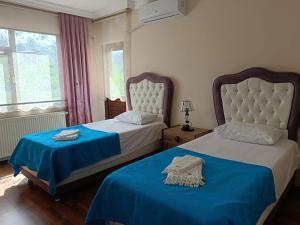 فيلا فاطمة في طرابزون: غرفة نوم بسريرين مع شراشف زرقاء ونافذة