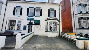 a white building with a bench in front of it at Delamere Hotel in Blackpool