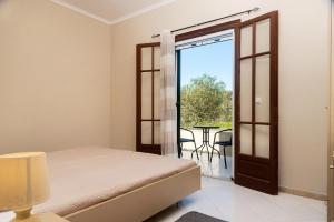 a bedroom with a bed and a balcony with a table at ELPIS appartment in Vitalades