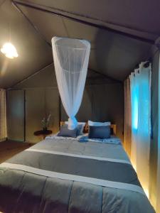 Schlafzimmer mit einem großen Bett und einem Moskitonetz in der Unterkunft Harmony Haven Eco Camp, Udawalawa in Udawalawe