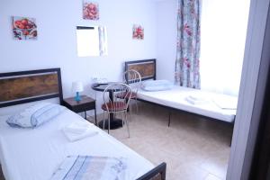 um quarto com 2 camas e uma mesa com uma cadeira em Taxi Hostel em Otopeni