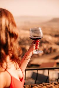 une femme tenant un verre de vin dans l'établissement Ages in Cappadocia, à Uçhisar