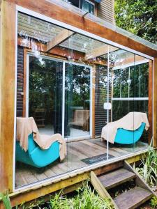 ein Glashaus mit zwei Stühlen auf einer Terrasse in der Unterkunft Tiny House II - Sítio dos Wolff in Gravataí