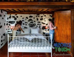 Dos personas de pie en un dormitorio con cama en O Pomar do Gasparinho, en Santa Cruz da Graciosa