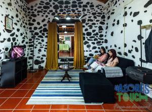 Tres mujeres sentadas en un sofá en una sala de estar en O Pomar do Gasparinho, en Santa Cruz da Graciosa