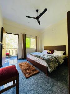 Shiv Shakti Yogpeeth Cottages في ريشيكيش: غرفة نوم بسرير ومروحة سقف