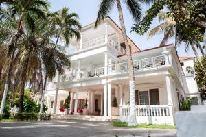 een wit huis met palmbomen ervoor bij Coconut Residence & Spa in Kololi