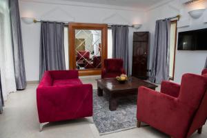 een woonkamer met 2 rode stoelen en een tafel bij Coconut Residence & Spa in Kololi