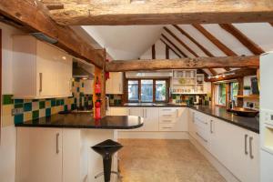 a kitchen with white cabinets and black counter tops at DADIO's Barn - Indoor Swimming Pool 400 Years Old & Hot tub in Kent