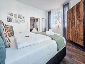 a white bedroom with a large bed and a window at Alpha Apartments in Dortmund