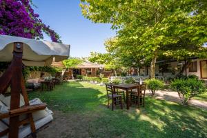 an outdoor patio with tables and chairs and trees at Armagrandi Hotel Bozcaada-Special Category in Bozcaada