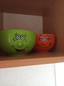 two green and orange bowls sitting on a shelf at Sunrise Caravan in Dymchurch