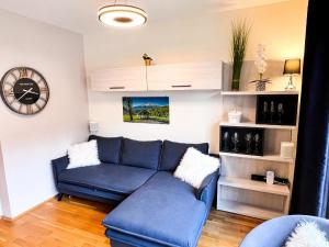ein Wohnzimmer mit einem blauen Sofa und einer Uhr in der Unterkunft Studio für 5 Personen ca 55 qm in Rauris, Salzburger Land Rauristal - b62137 in Rauris