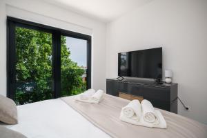 een witte slaapkamer met een tv en een bed met witte handdoeken bij "Golden Sky"Rooftop Pool Villa in Vodice +70 foto's
