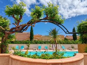 a swimming pool with chairs and a tree and a fence at Résidence l'Oustal des Mers in Gruissan