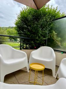 2 chaises blanches et une table jaune sur un balcon dans l'établissement Appartement proche centre parking & terrasse, à Besançon