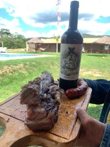 a bottle of wine and a piece of meat on a table at Hotel campestre santa rita 