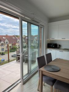 a kitchen with a table and a large sliding glass door at Baltic Vip Nowe Apartamenty blisko plaży in Rewal