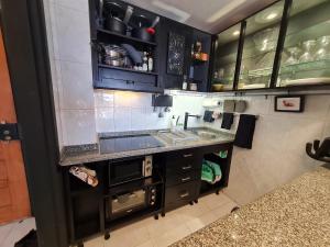 uma cozinha com armários pretos e um lavatório em Beach Addiction em Costa da Caparica
