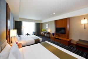 um quarto de hotel com duas camas e uma televisão de ecrã plano em Fullon Hotel Tamsui Fishermen's Wharf em Tamsui