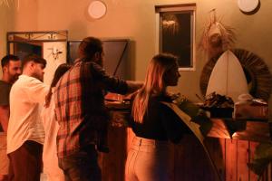 a group of people standing in a room with a surfboard at Playa Del Sol Surf House in Tamraght Ouzdar
