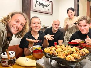 a group of people sitting around a table with food at Guest House Pongyi in Kanazawa