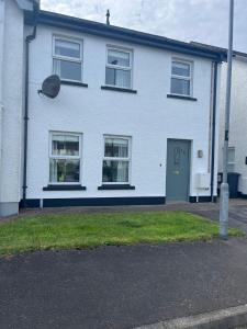 uma casa branca com uma porta verde e janelas em Port Miller em Portstewart