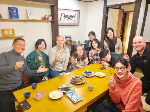 a group of people sitting around a table at Guest House Pongyi in Kanazawa