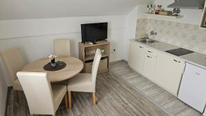 a small kitchen with a wooden table and a television at Apartment Andrea in Smoljanac