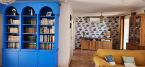 uma prateleira de livros azuis numa sala de estar com um sofá em Villa en bord de mer face à l'Ile de Porquerolles em Hyères