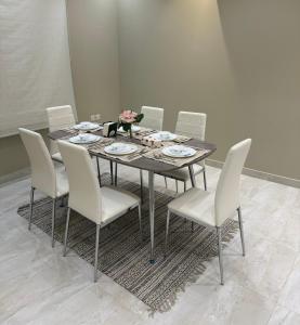 Elegant Apartment in Al-Narjis شقة أنيقة بثلاث غرف وصالة تسجيل ذاتي في الرياض: طاولة طعام مع كراسي بيضاء وورود عليها