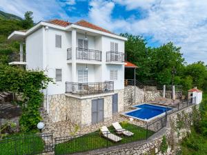 a white house with a swimming pool and two chairs at Villa Tranquila in Budva