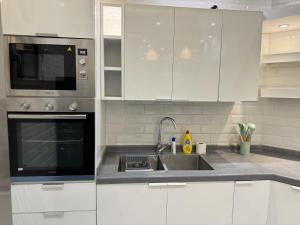 Biała kuchnia ze zlewem i kuchenką mikrofalową w obiekcie Elegant Apartment in Al-Narjis شقة أنيقة بثلاث غرف وصالة تسجيل ذاتي w Rijadzie