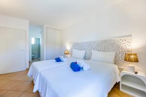 ein Schlafzimmer mit einem weißen Bett mit blau ausgestopften Tieren in der Unterkunft Apartamentos Turisticos Vila Palmeira in Lagos