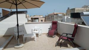 a patio with chairs and an umbrella on a roof at La Casa Delle Conchiglie in Trapani