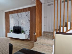 a living room with a staircase and a television at Town Square House in Gevgelija