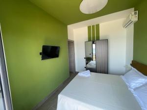 um quarto com uma parede verde, uma cama e uma televisão em Il Vicoletto Bovalino - B&B em Bovalino Marina