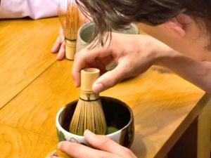 una persona sosteniendo un cepillo en una taza en Guest House Pongyi, en Kanazawa