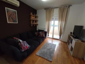 a living room with a black couch and a television at Anthurium - SelfCheckIn - Nomad in Zagreb