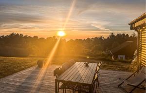 a wooden deck with a table and chairs at sunset at Gorgeous Home In Fårevejle With Kitchen in Fårevejle