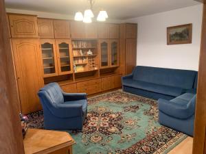 Una sala de estar con un sofá azul y dos sillas. en Callatis Suite, en Mangalia