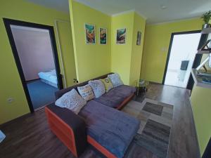a living room with a brown couch and yellow walls at AMRI Apartman in Balatonföldvár