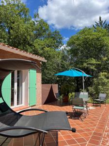 eine Terrasse mit Stühlen und einem Sonnenschirm neben einem Haus in der Unterkunft Natur & Jasmin Chambres d'hôtes naturistes en Provence in Lorgues