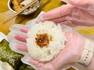 a person holding a piece of rice in their hand at Guest House Pongyi in Kanazawa